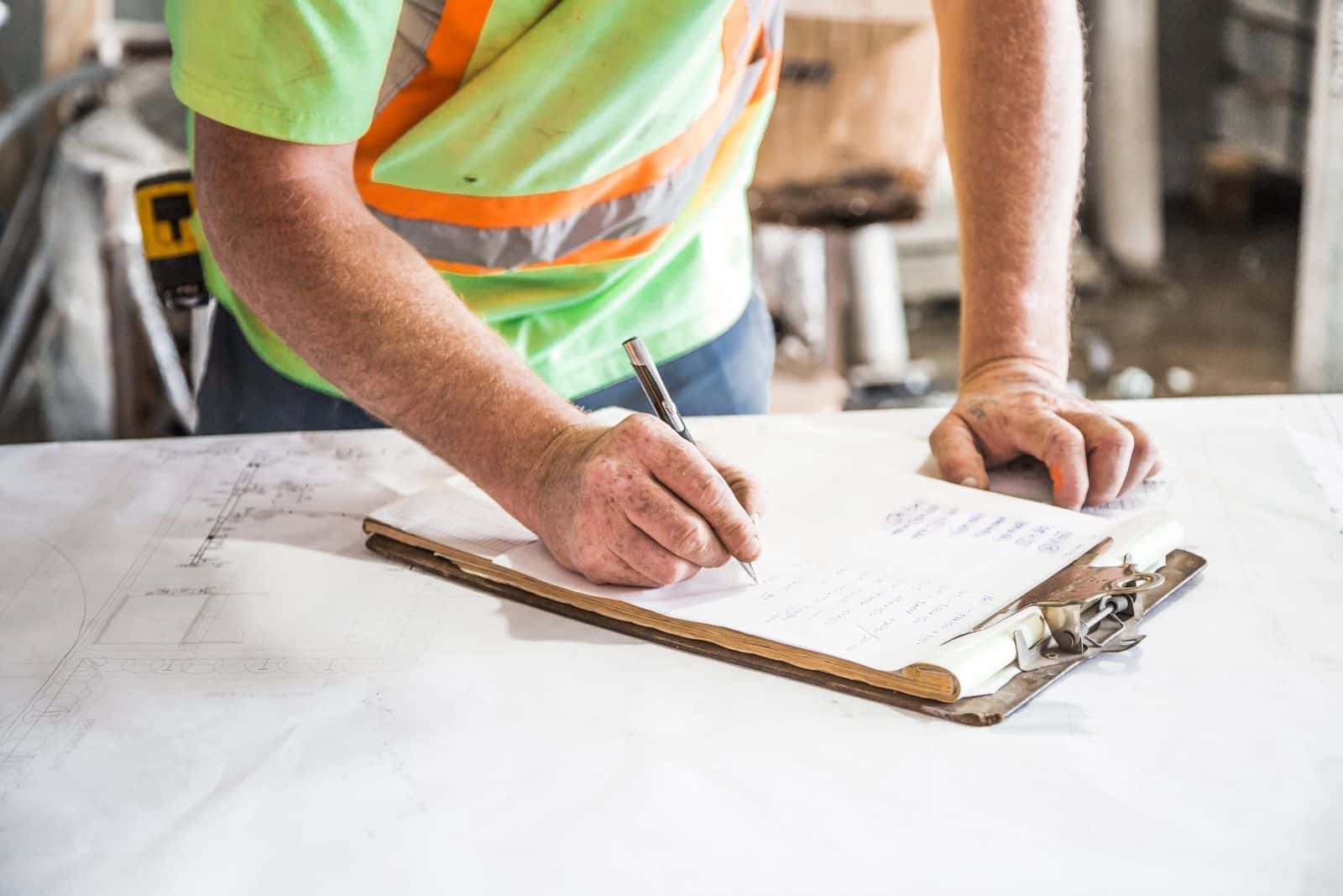 A contractor filling in paperwork on site drawings