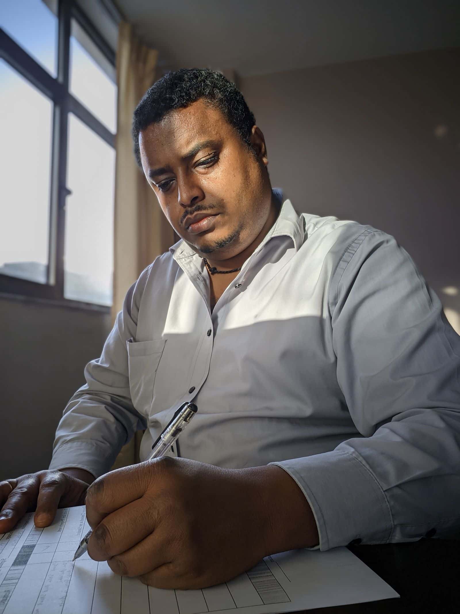 Someone filling in a form at a desk beside a window