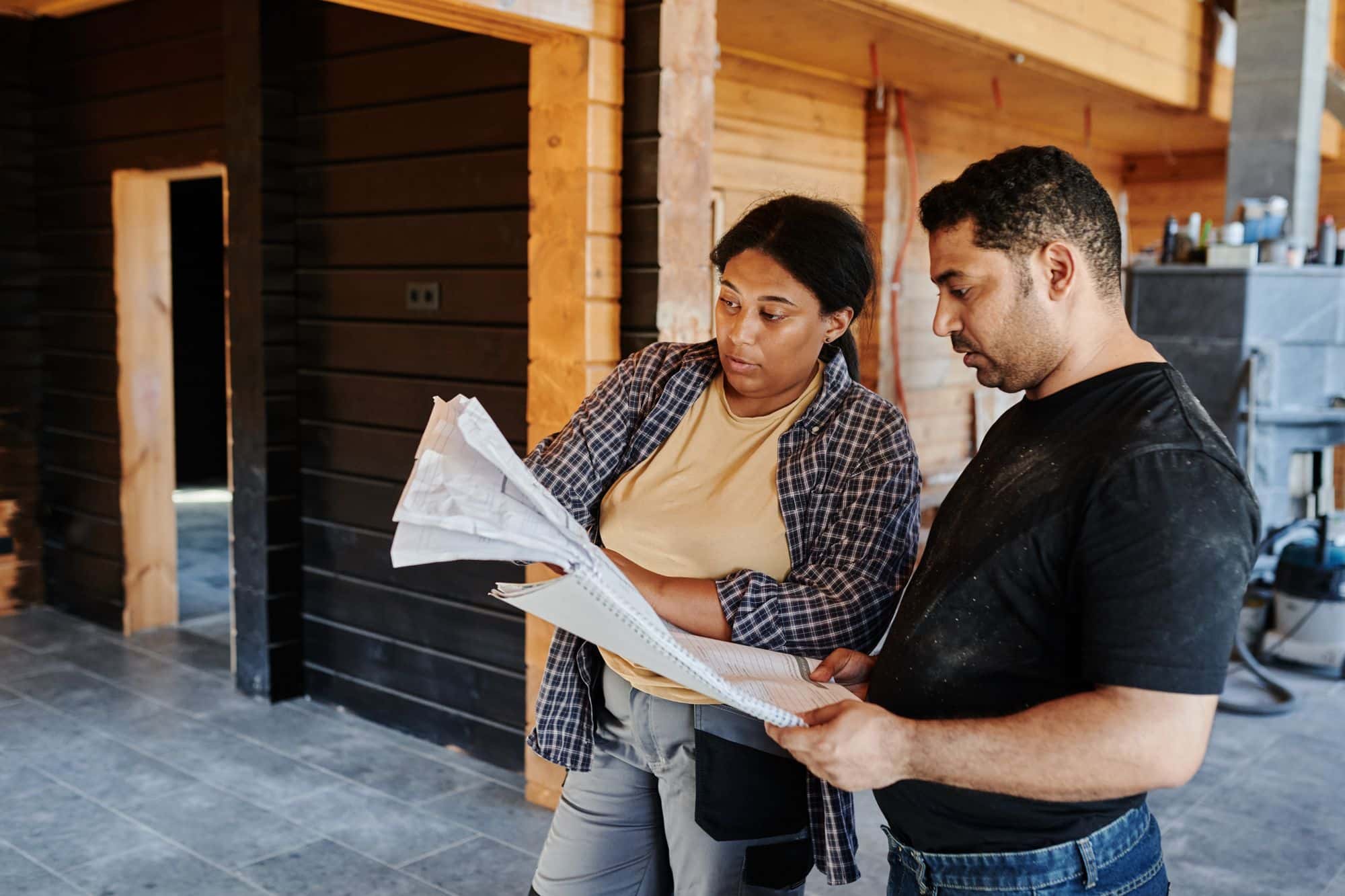 Two people going over a set of drawings inside a timber framed building