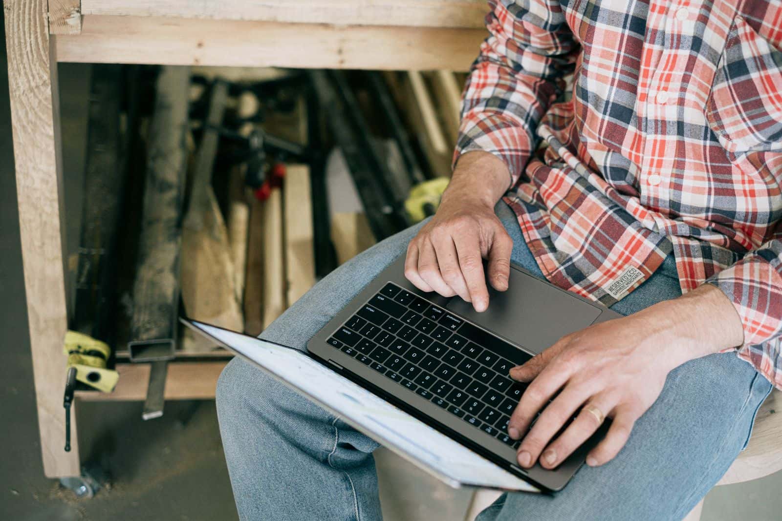 A tradesman using a laptop at a bench in a workshop