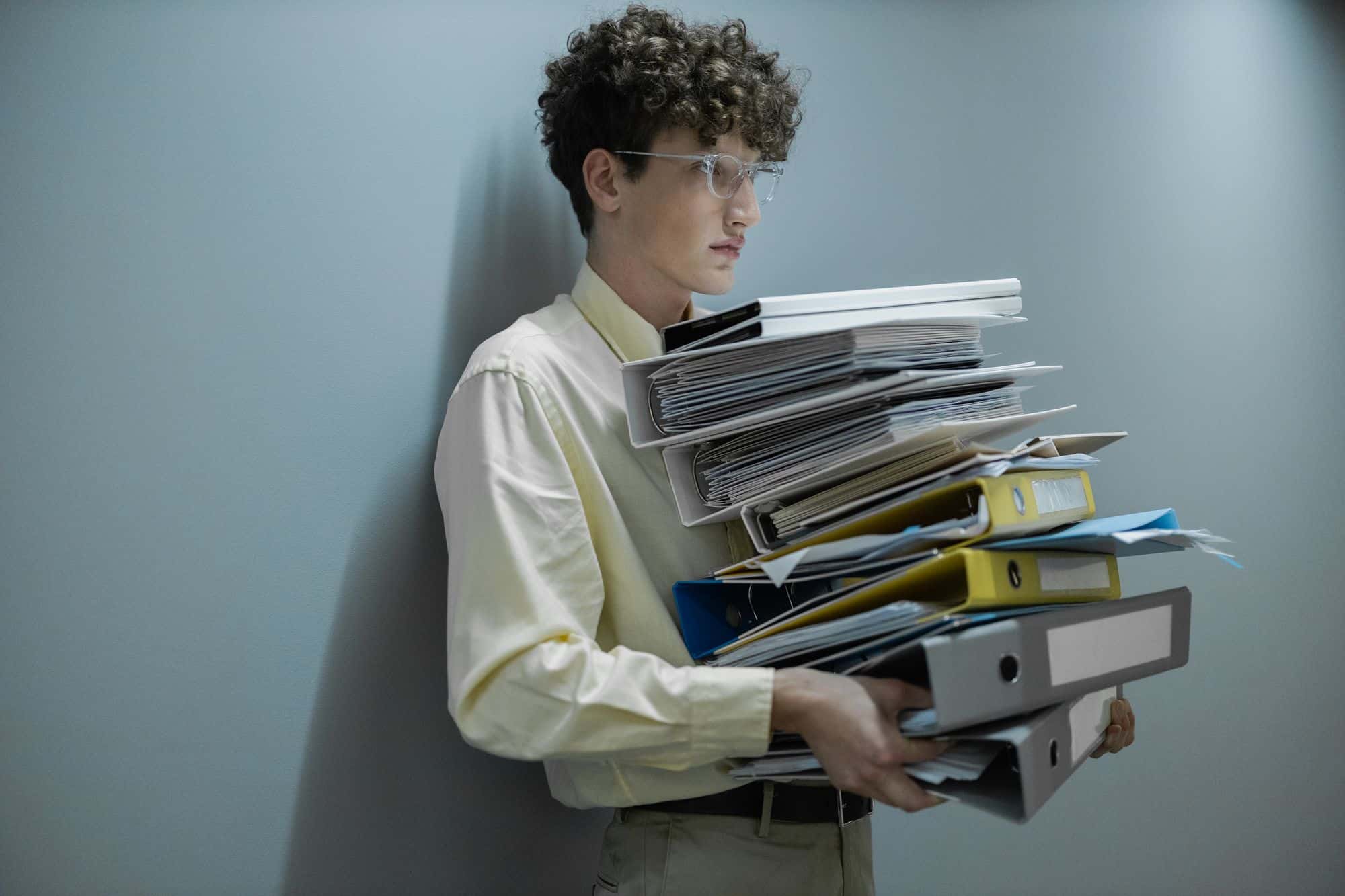 A man carrying an armful of ring binders and paperwork