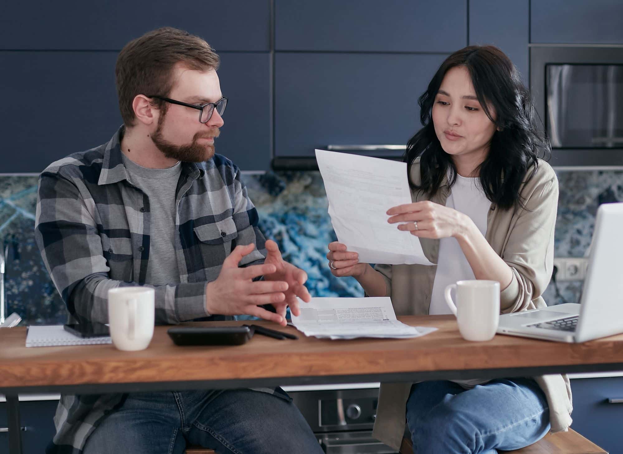 Two people at a kitchen counter going through a letter and paperwork