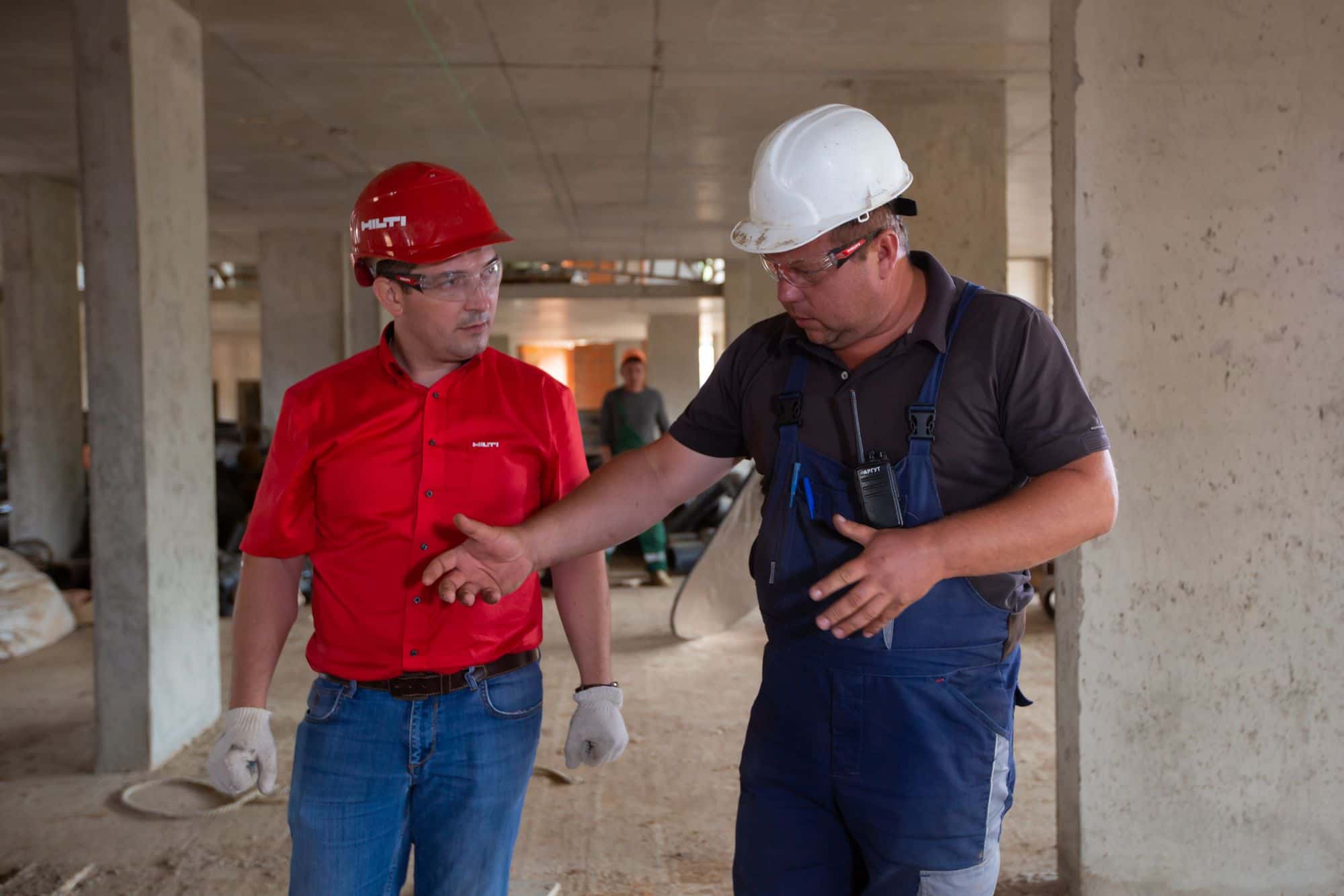 Two workers in hard hats talking on site