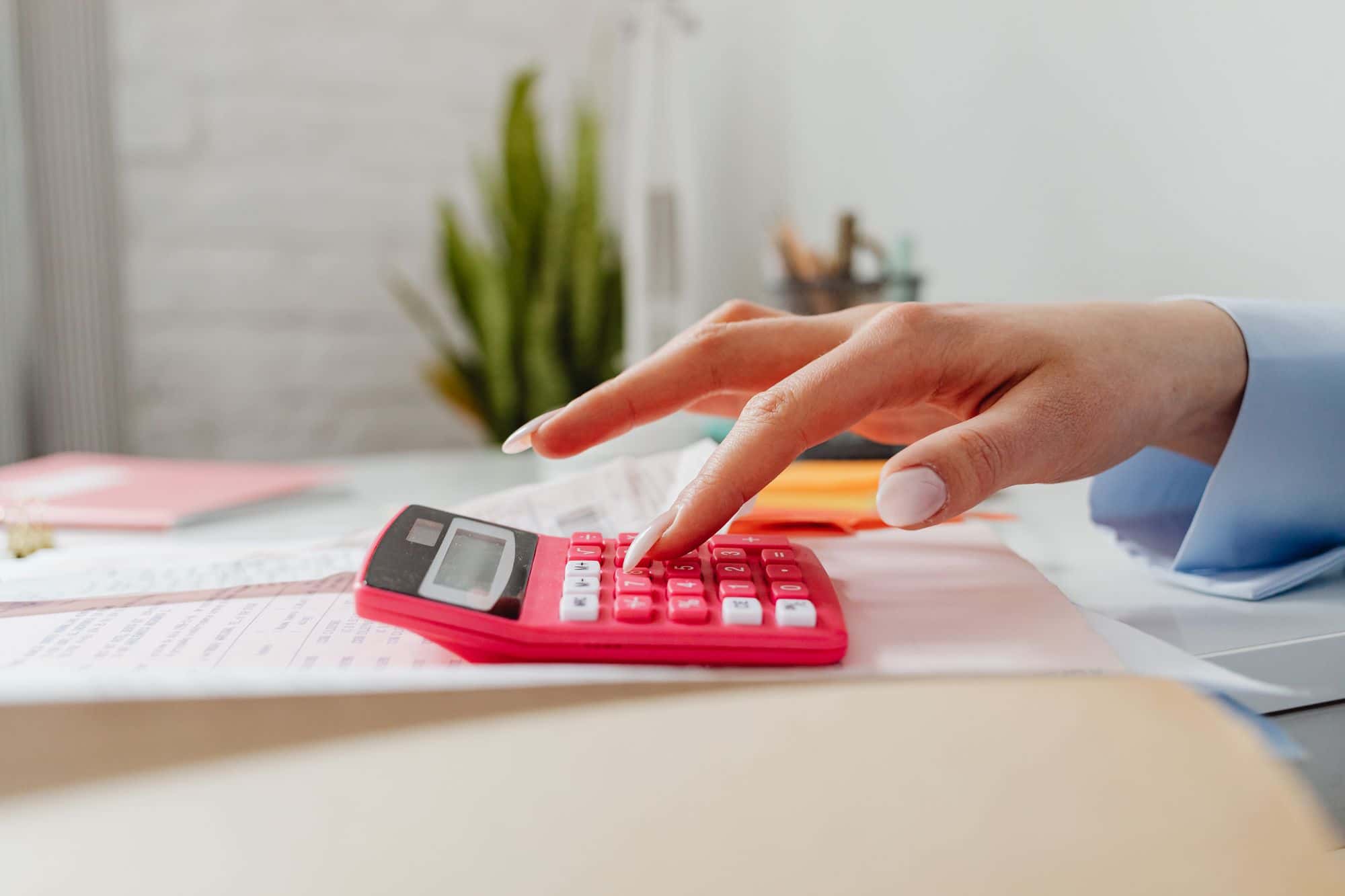 A hand working out a figure on a desk calculator